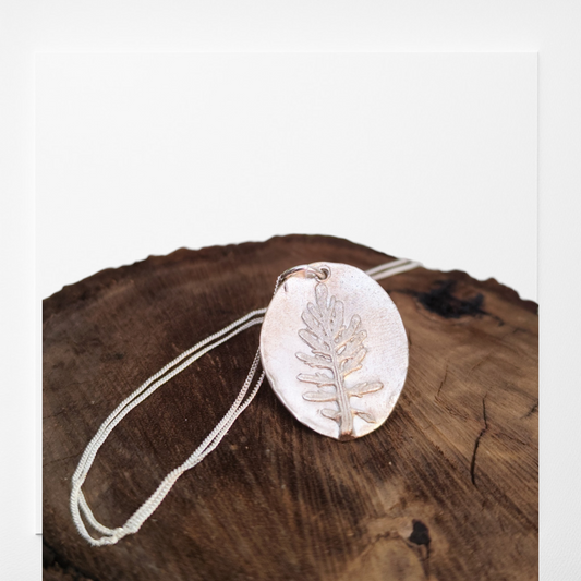 Medalla de plata con huella de hoja de coronas de reina en relieve y cadena fina