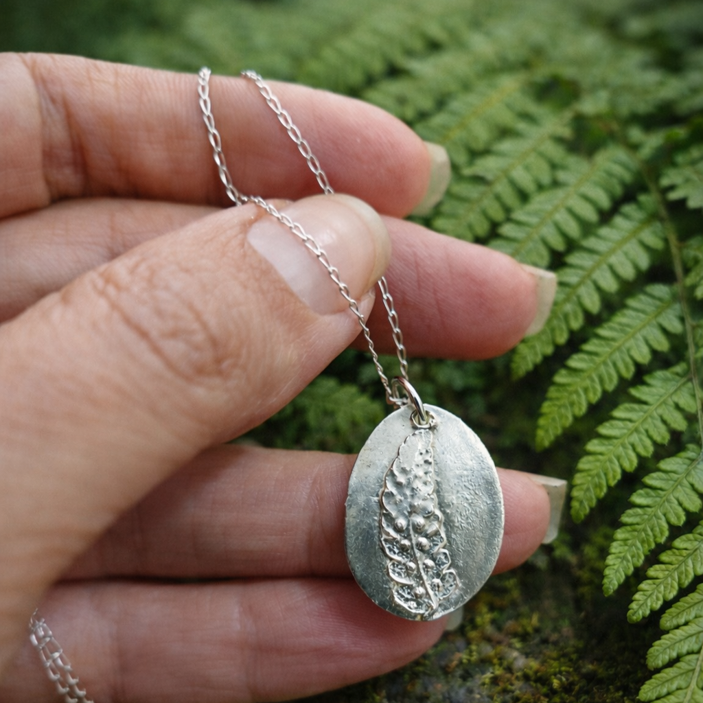 Medalla de plata con huella de hoja de helecho en relieve y cadena fina