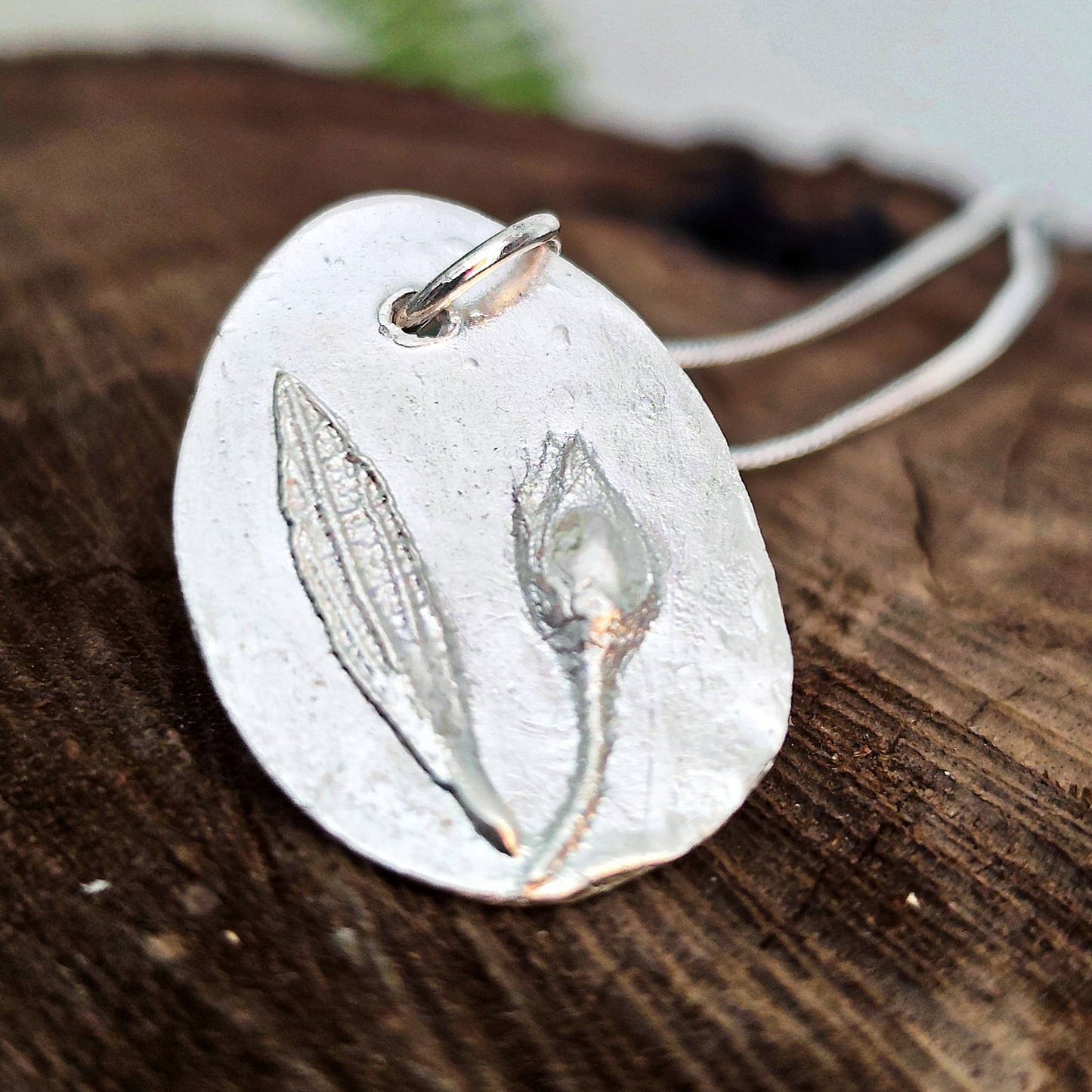 Detalle del relieve de capullo y hoja de jara en colgante de plata artesanal