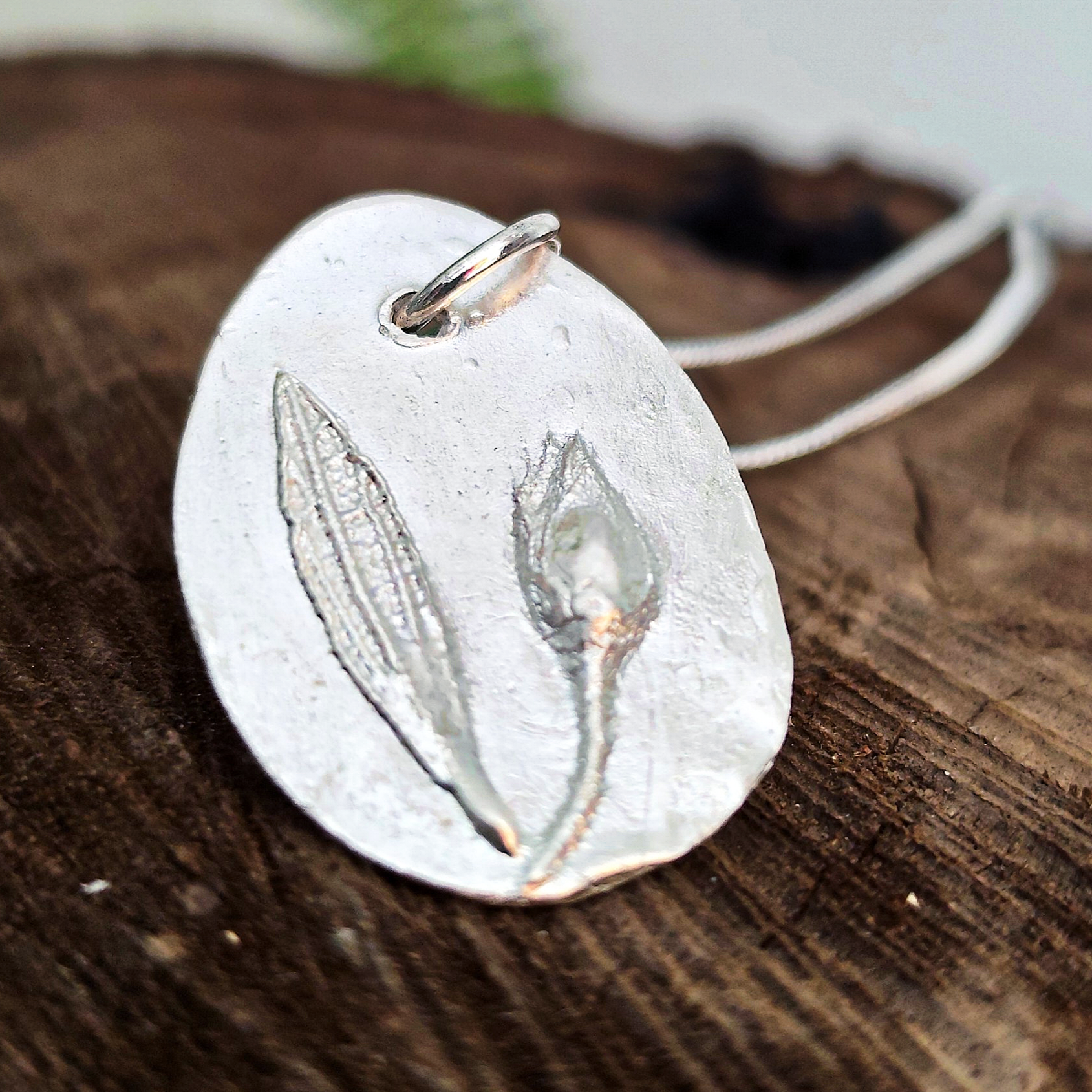 Detalle del relieve de capullo y hoja de jara en colgante de plata artesanal