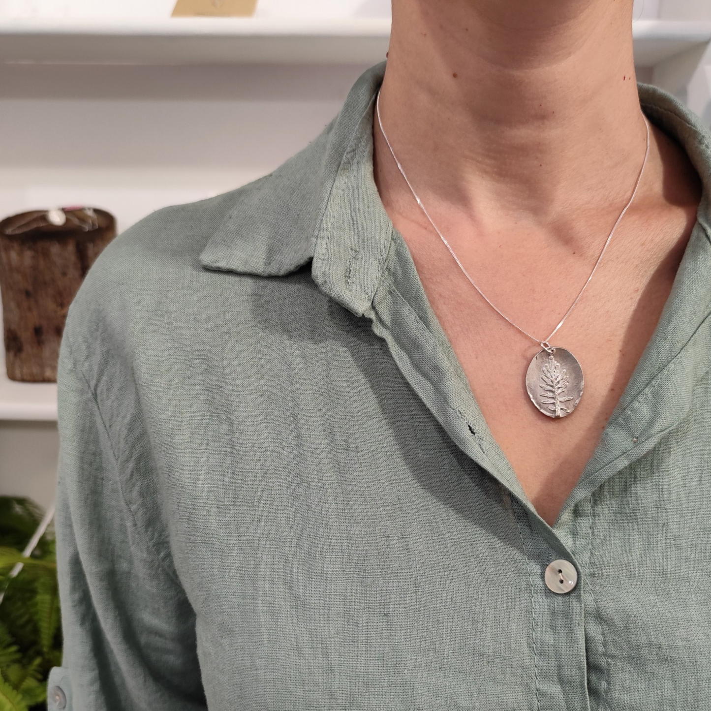 Mujer con colgante de plata con hoja de coronas de reina en relieve y cadena fina