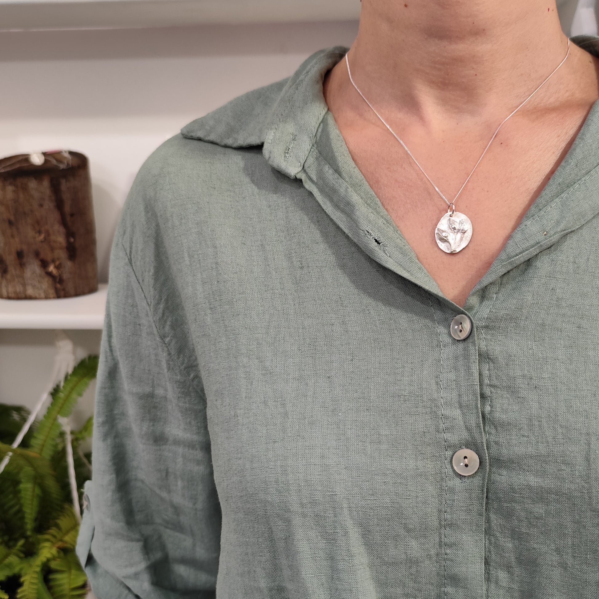 Mujer con colgante de plata con tres capullos de jara en relieve y cadena fina