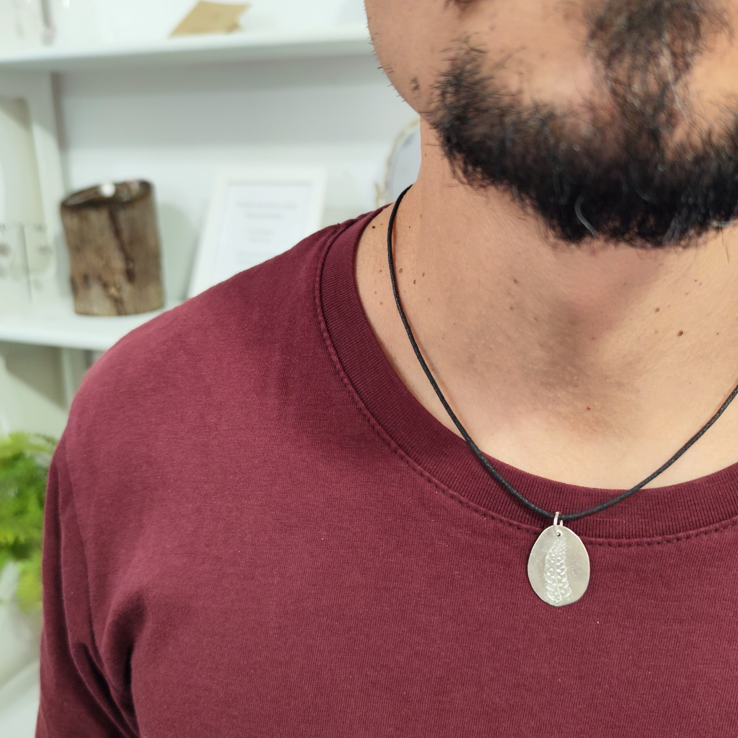 Hombre con medalla de plata con huella de helecho en relieve y cordón negro de algodón