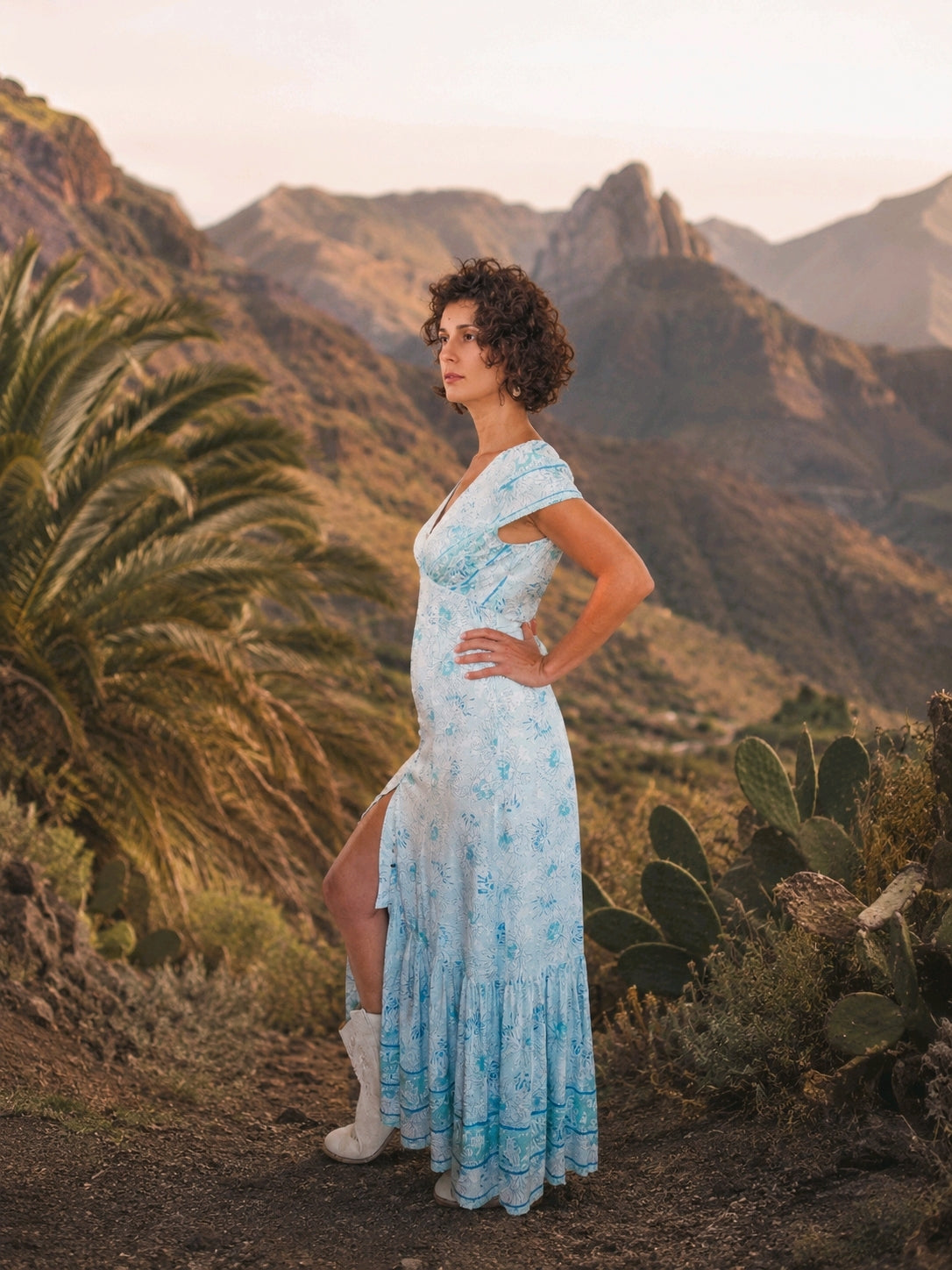 Mujer con Vestido Acuarela largo estampado en tonos turquesa y verde en un paisaje montañoso de La Gomera.