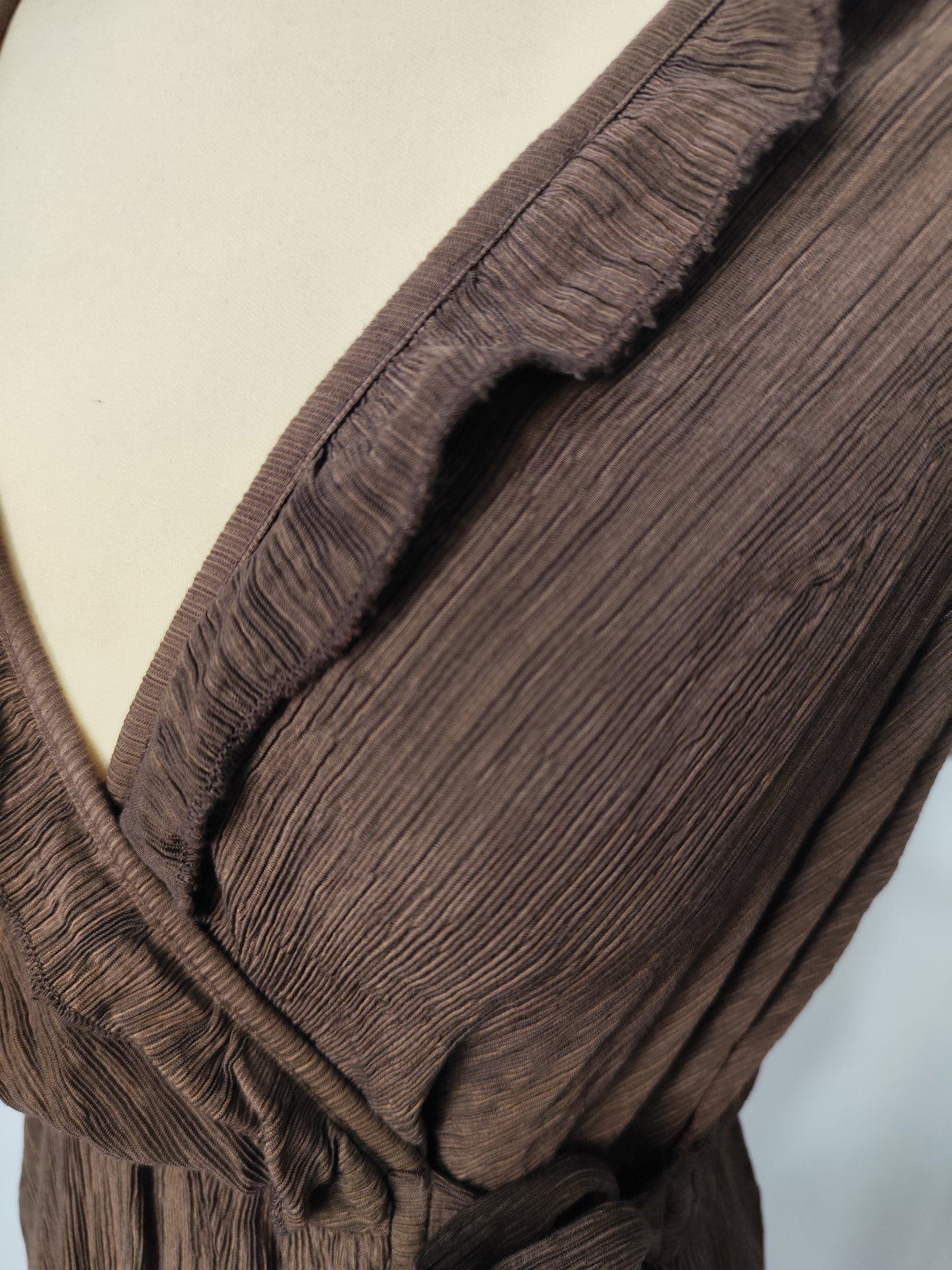 Detalle del tejido plisado, el escote cruzado y el volante del vestido Amapola.
