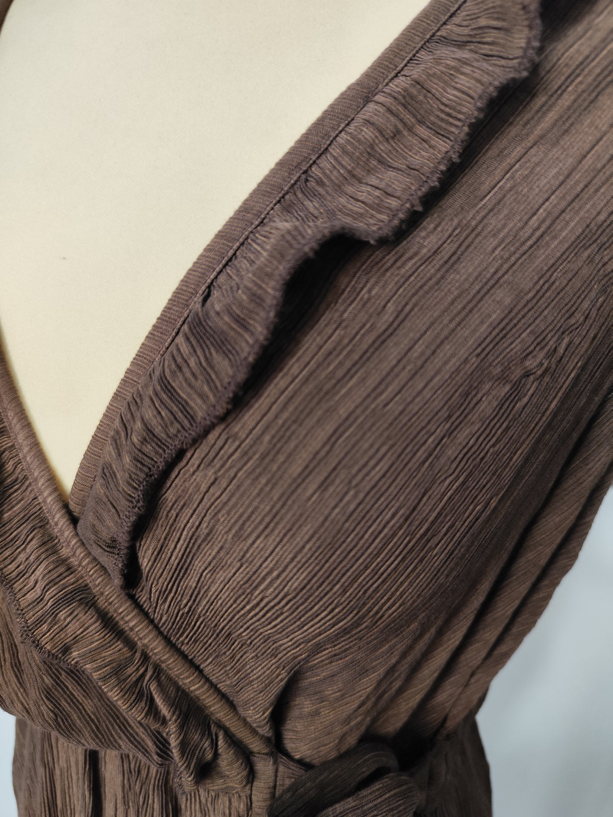 Detalle del tejido plisado, el escote cruzado y el volante del vestido Amapola.