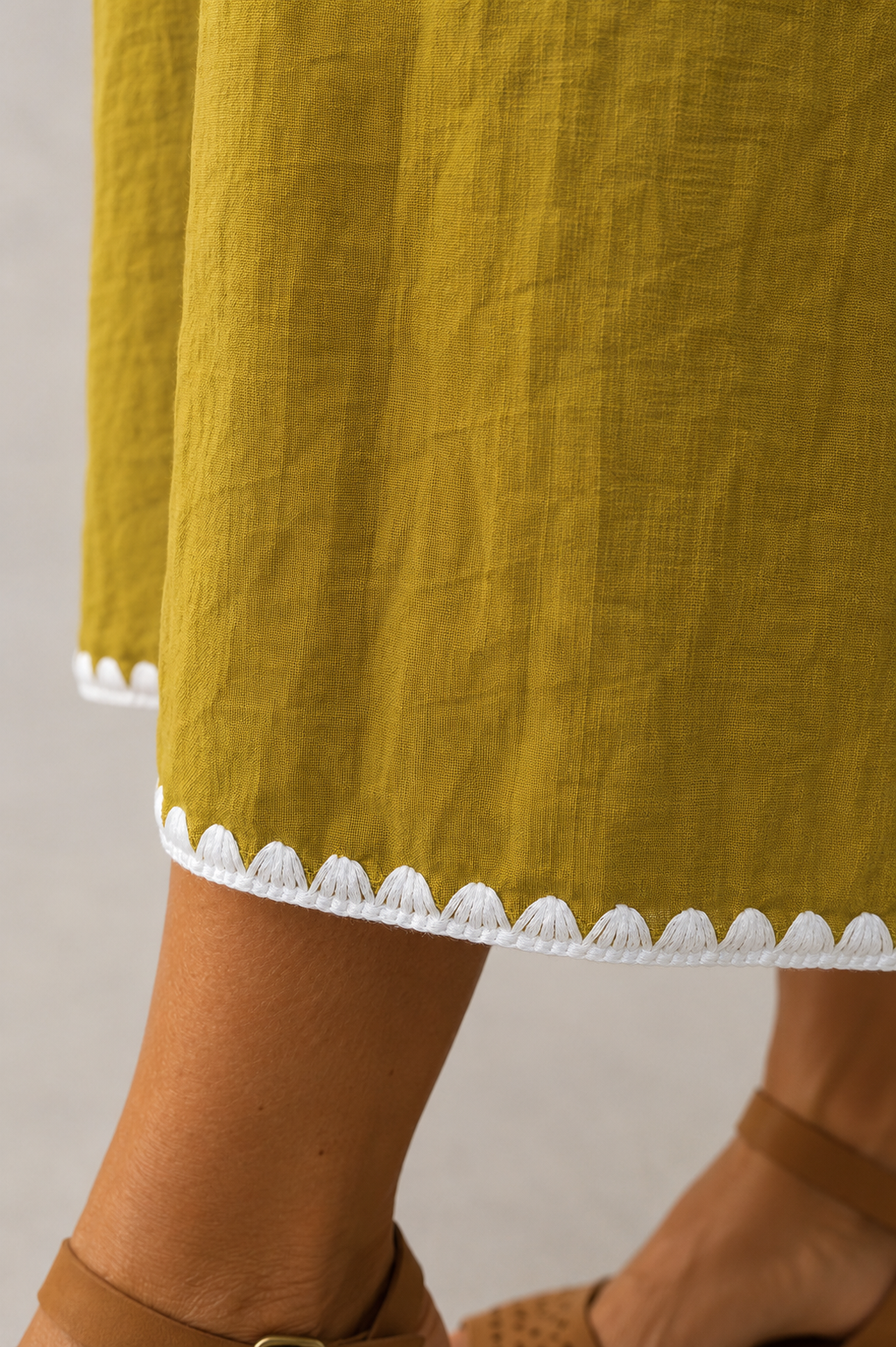 Detalle del tejido del vestido Garoé y puntilla decorativa blanca en el bajo